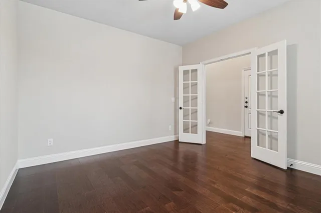 an empty room with wooden floor chandelier fan and windows