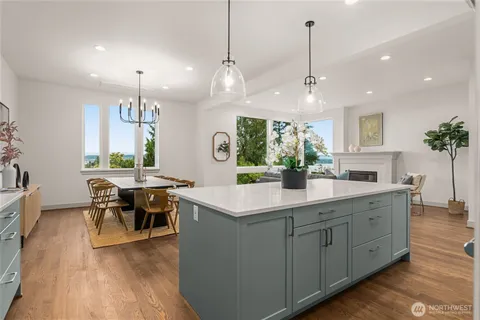 a kitchen with stainless steel appliances kitchen island a large island in the center a sink a window and chairs
