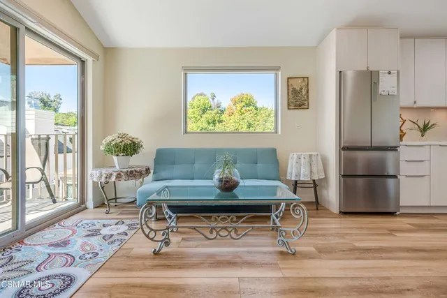 a living room with stainless steel appliances furniture a rug and a large window