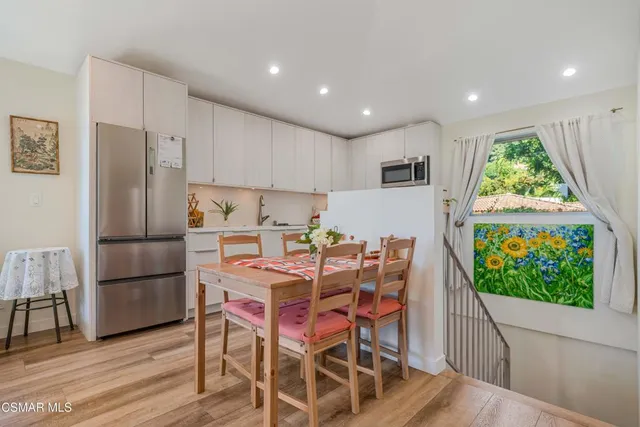 a kitchen with stainless steel appliances a refrigerator a stove a microwave oven with a dining table and chairs with wooden floor