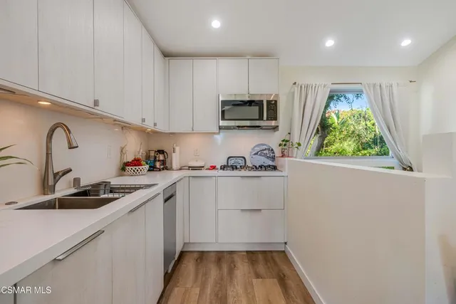 a kitchen with kitchen island a sink appliances cabinets and a window