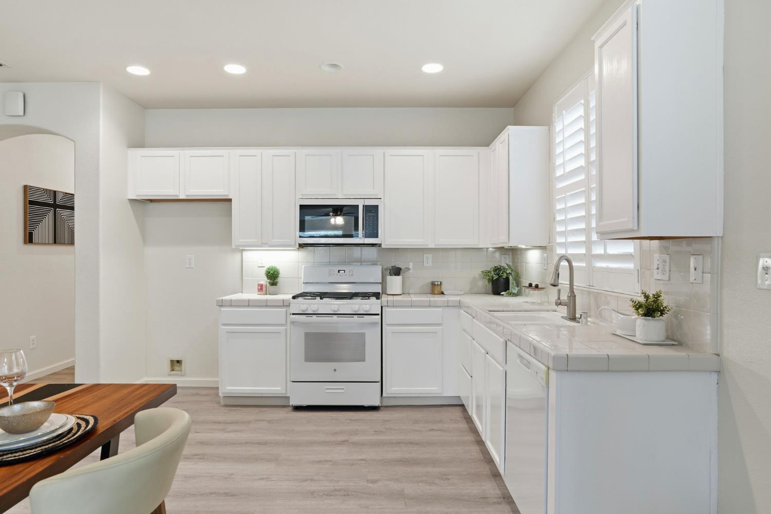10250 Rudder Way Stockton, CA 95209 - Photo 13 of 46 a kitchen with stainless steel appliances granite countertop a refrigerator a stove top oven a sink dishwasher and white cabinets with wooden floor