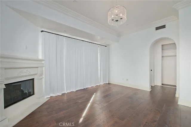 an empty room with wooden floor fireplace and windows