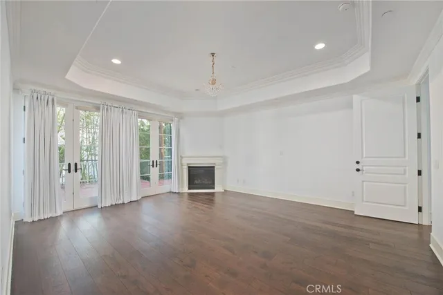 an empty room with wooden floor fireplace and windows