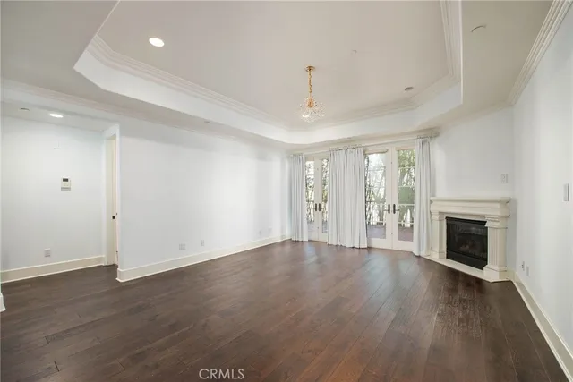 a living room with a fireplace large windows and wooden floor