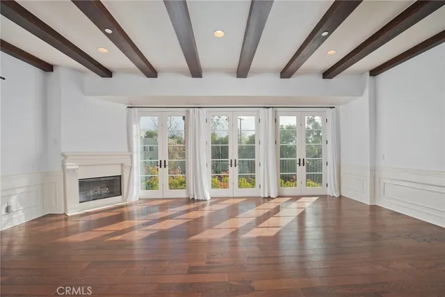 a view of an empty room with wooden floor fireplace and a window