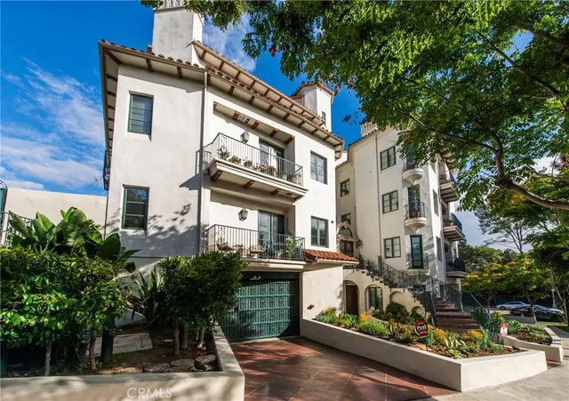 a view of a white building among the street with palm trees