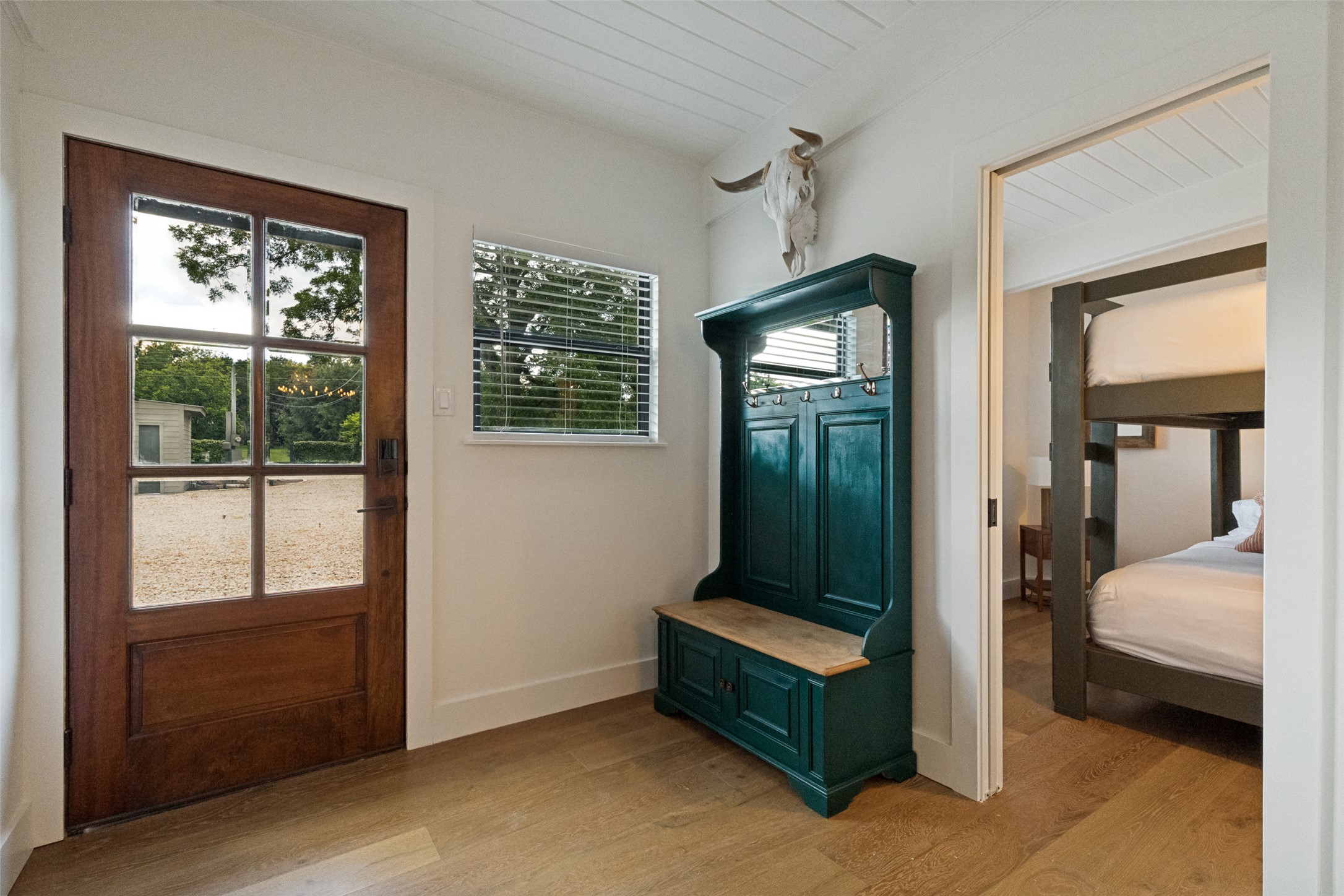 303 Lago Verde Road Austin, TX 78734 - Photo 5 of 39 A welcoming entry features hardwood floors, a sturdy wooden door, and a glimpse into a charming bedroom.