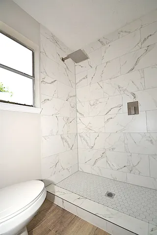 a white toilet sitting next to a shower