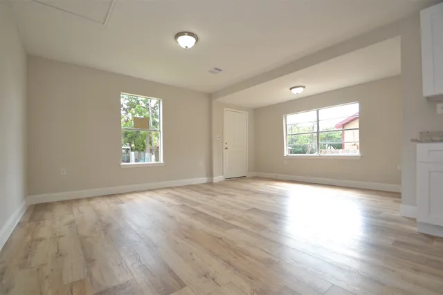 an empty room with wooden floor and windows