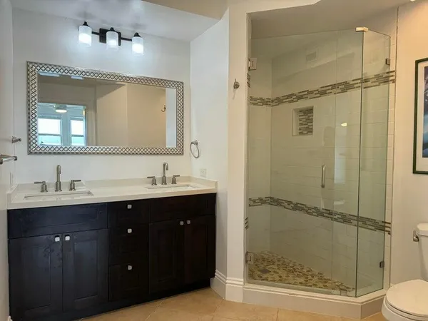 a bathroom with a double vanity sink toilet mirror and shower