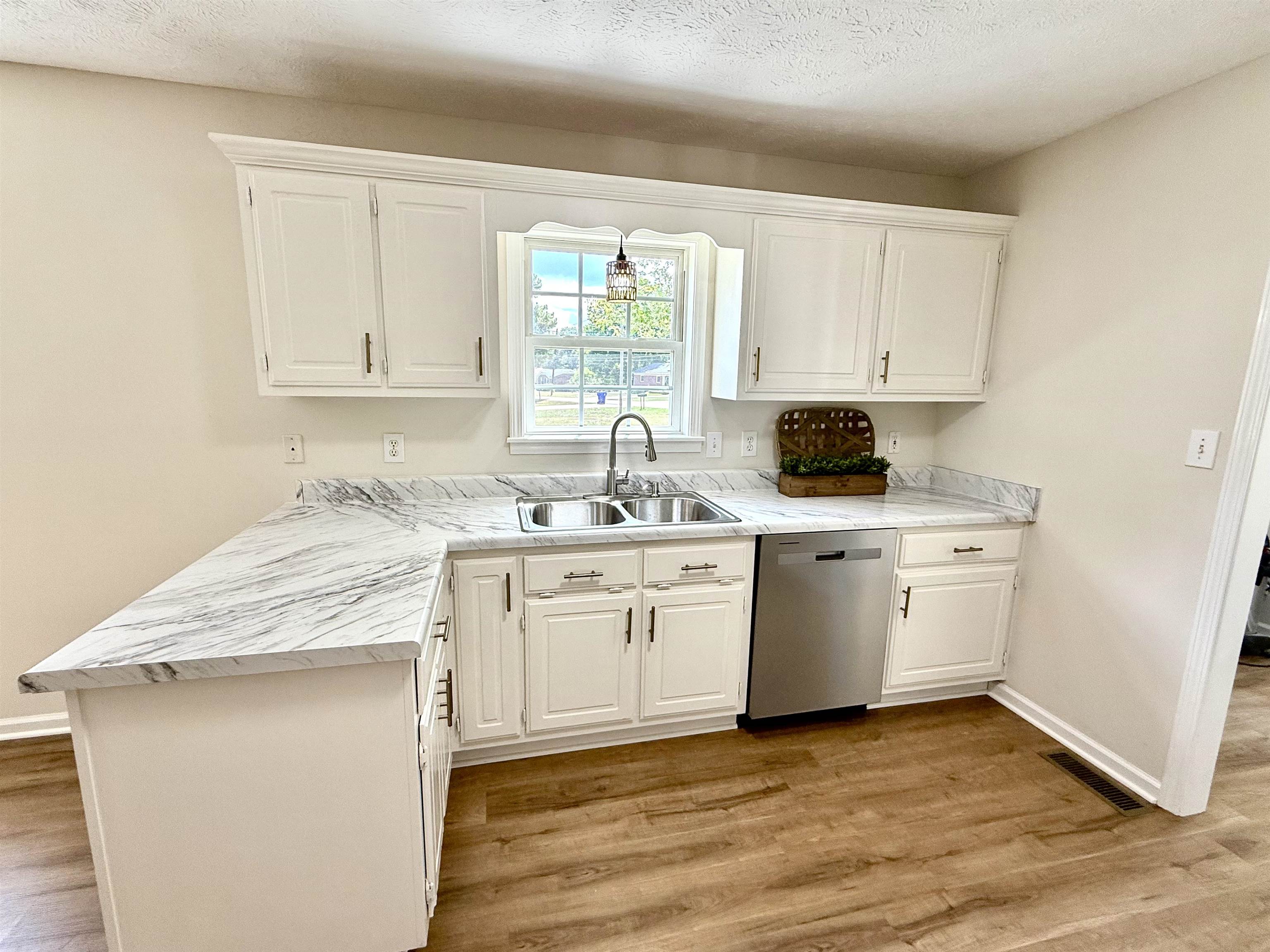 1250 Clifton Road Savannah, TN 38372 - Photo 4 of 33 Kitchen featuring light countertops, white cabinetry, light wood finished floors, dishwasher, and a textured ceiling