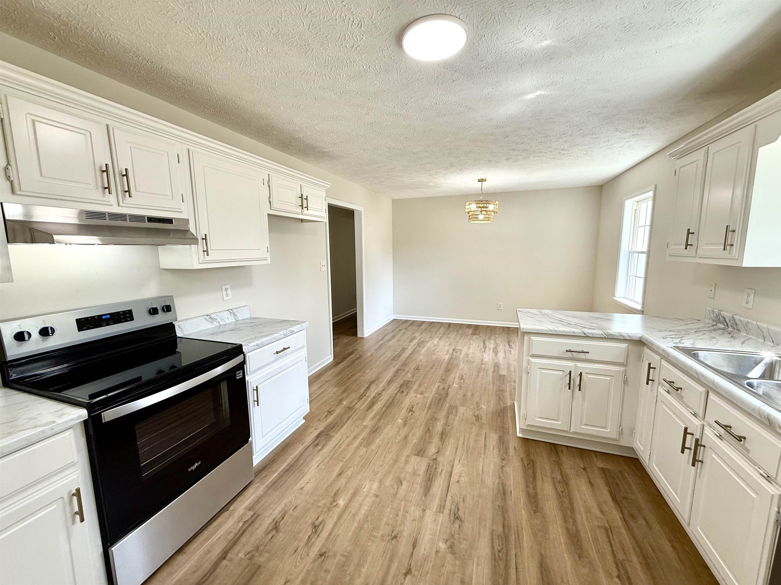 1250 Clifton Road Savannah, TN 38372 - Photo 5 of 33 Kitchen featuring stainless steel range with electric cooktop, light countertops, a peninsula, white cabinetry, and a textured ceiling