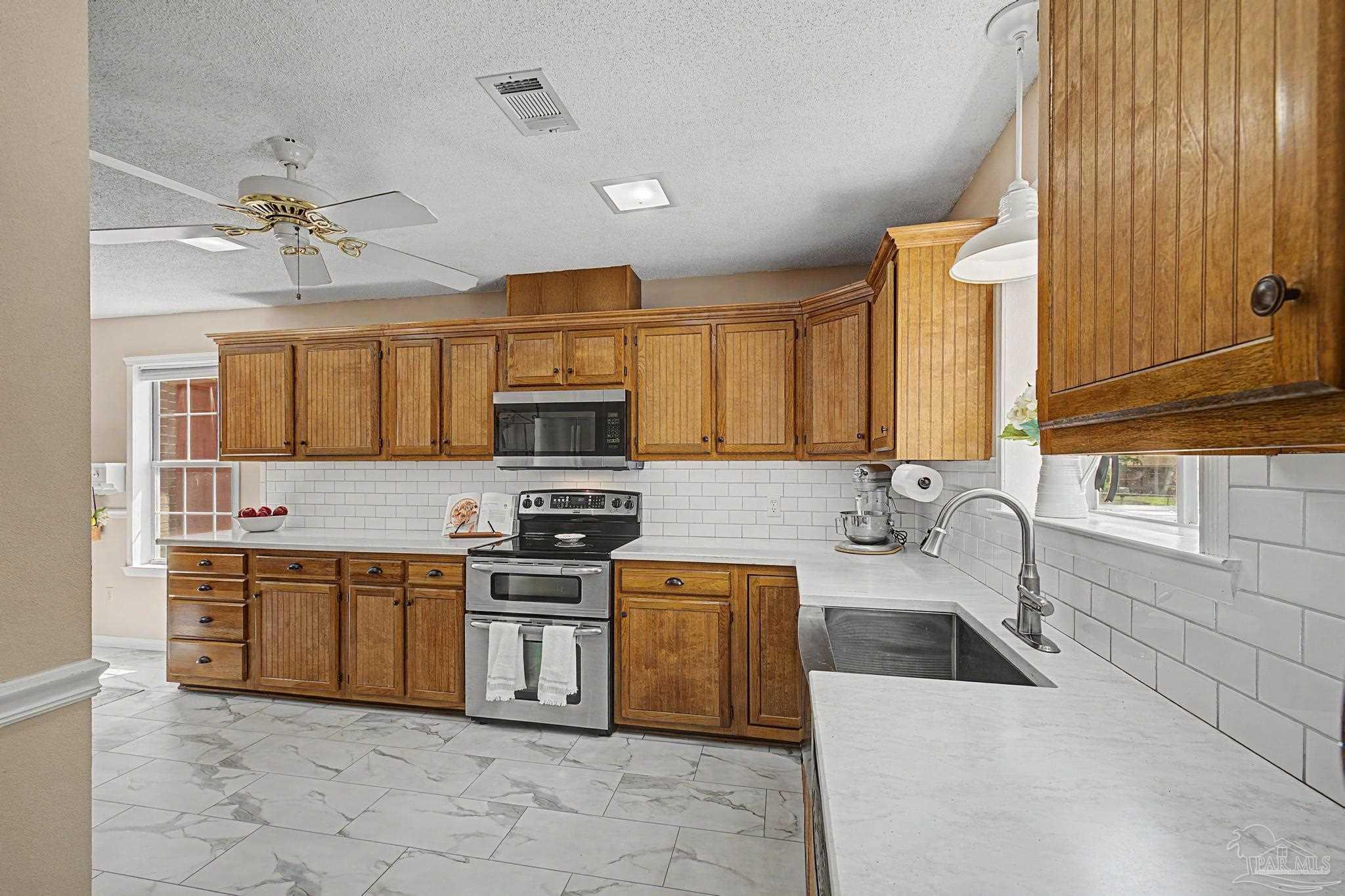 4959 Skipper Lane Pace, FL 32571 - Photo 14 of 51 a kitchen with stainless steel appliances granite countertop a stove top oven a sink dishwasher and a refrigerator with wooden cabinets