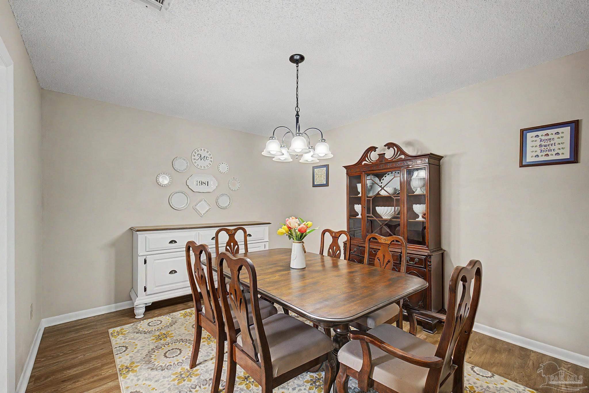 4959 Skipper Lane Pace, FL 32571 - Photo 17 of 51 a view of a dining room with furniture a chandelier and wooden floor