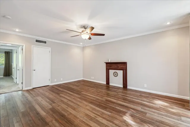 a view of an empty room with window and wooden floor