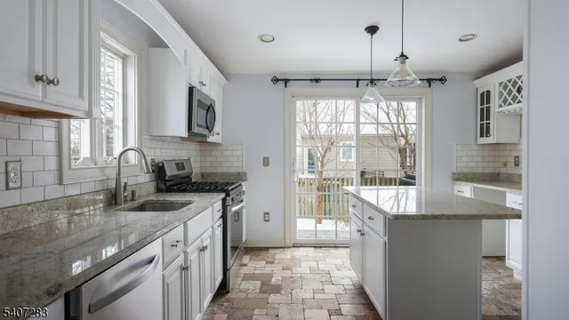 a kitchen with granite countertop a sink stainless steel appliances and cabinets