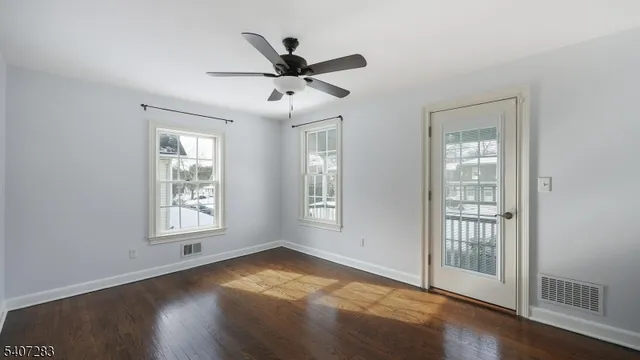 a view of empty room with wooden floor and fan