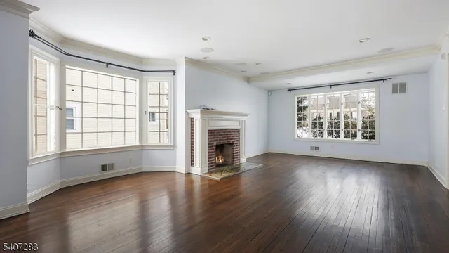 an empty room with wooden floor fireplace and windows