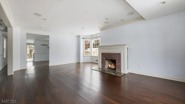 an empty room with wooden floor fireplace and windows