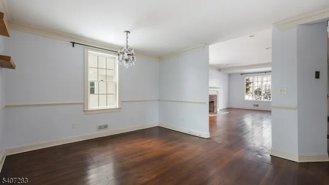 an empty room with wooden floor chandelier and windows