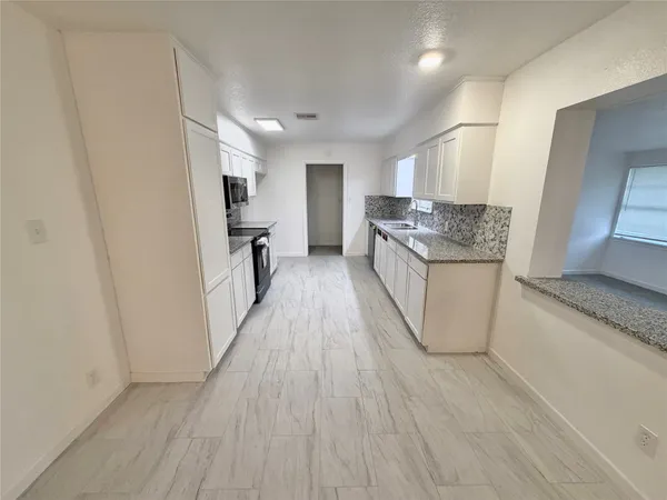a kitchen with white cabinets granite counter tops and white appliances