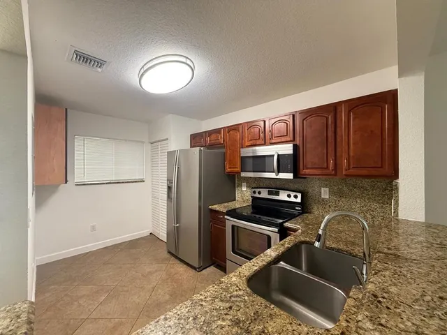 a kitchen with stainless steel appliances granite countertop a refrigerator stove and sink