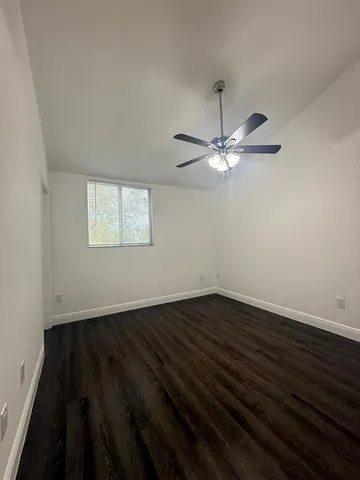 a view of a room with wooden floor and a ceiling fan