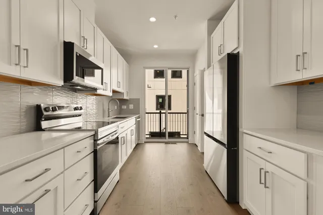 a large kitchen with stainless steel appliances granite countertop a refrigerator and a stove top oven