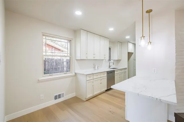 a hallway view with stainless steel appliances granite countertop a sink and dishwasher