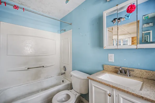 a bathroom with a granite countertop sink mirror vanity and toilet