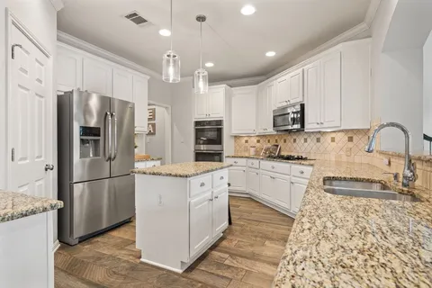 a kitchen with stainless steel appliances granite countertop a refrigerator sink and cabinets