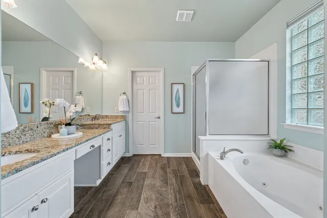 a spacious bathroom with a granite countertop tub sink shower and mirror