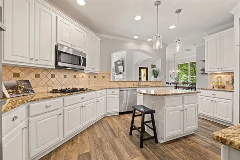 a kitchen with kitchen island granite countertop a sink cabinets and stainless steel appliances