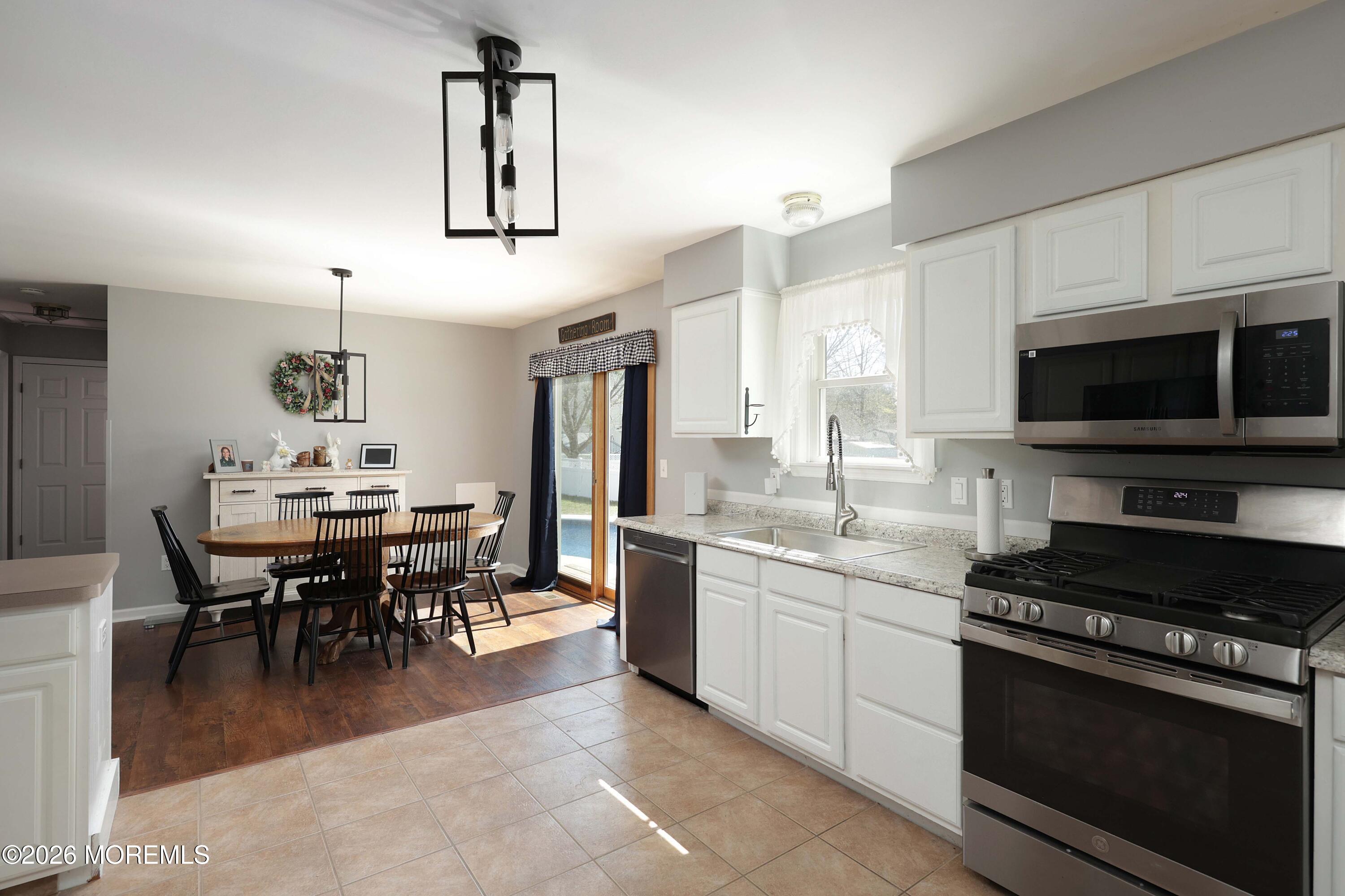 96 Atrium Drive Brick, NJ 08723 - Photo 12 of 39 a kitchen with stainless steel appliances granite countertop a stove top oven a sink a dining table and chairs
