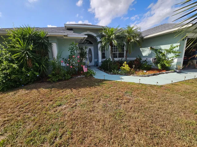 a view of a house with potted plants and a yard