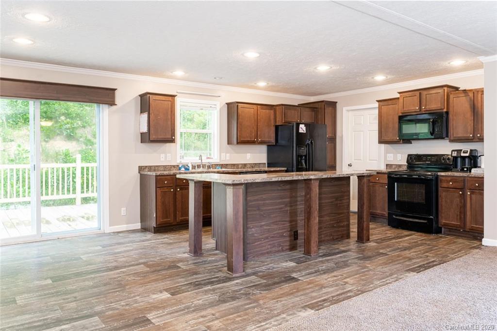354 Lost Cove Road Clyde, NC 28721 - Photo 3 of 13 a kitchen with stainless steel appliances kitchen island granite countertop a stove top oven a sink dishwasher a dining table and chairs with wooden floor