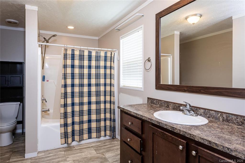 354 Lost Cove Road Clyde, NC 28721 - Photo 8 of 13 a bathroom with a granite countertop sink a toilet a mirror and shower