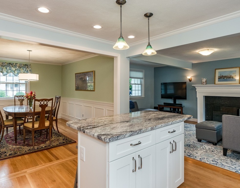 27 Hayes Road Concord, MA 01742 - Photo 8 of 18 a view of a dining room and a livingroom with furniture wooden floor a rug a fireplace and a chandelier