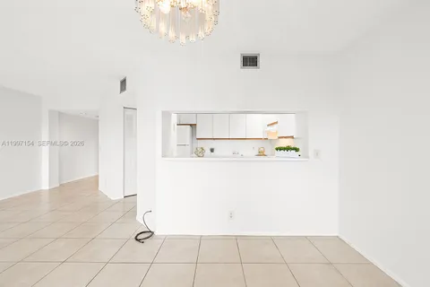 a view of a refrigerator in kitchen and an empty room