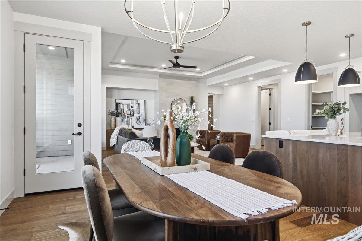 6762 South Messner Way Meridian, ID 83642 - Photo 13 of 35 Open-concept living space featuring wood-finish flooring, a tray ceiling with recessed lighting, and a modern chandelier