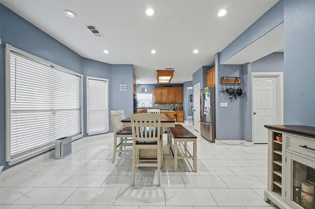a kitchen with stainless steel appliances kitchen island granite countertop dining table chair and a refrigerator