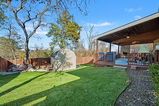 a view of a backyard with table and chairs potted plants and a large tree