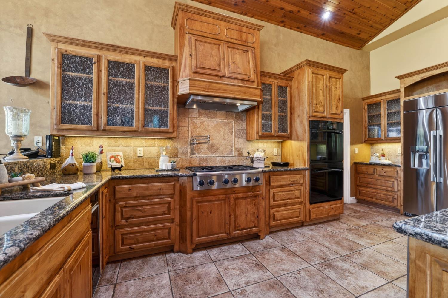 7021 Horseshoe Bar Road Loomis, CA 95650 - Photo 11 of 77 The warm custom Alder Wood cabinetry and statement range hood anchor this spacious kitchen, complemented by stone countertops, stainless steel appliances and rich wood ceilings.