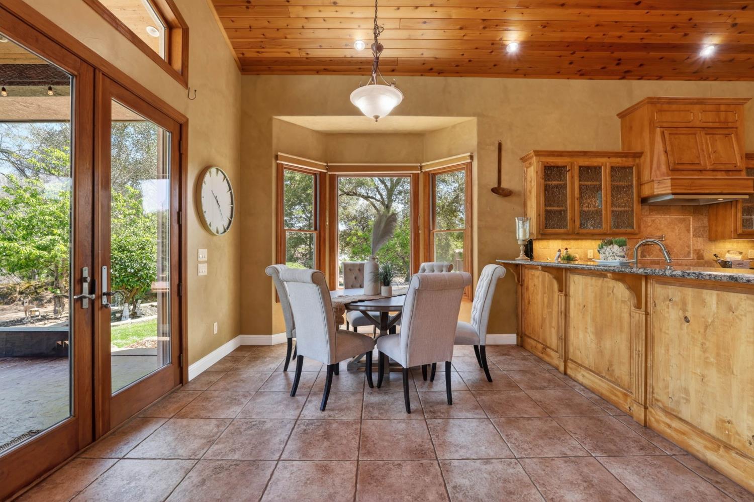 7021 Horseshoe Bar Road Loomis, CA 95650 - Photo 13 of 77 Bright kitchen nook with scenic views pairs beautifully with an extended counter offering ample space for gathering and entertaining, while the double glass doors provide seamless indoor-outdoor access.