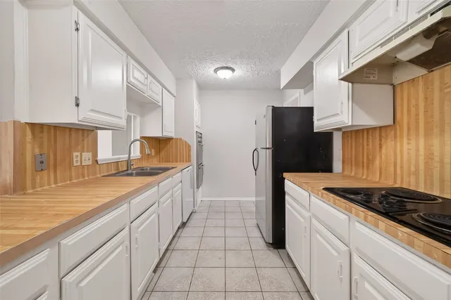 a kitchen with granite countertop a sink stove and refrigerator