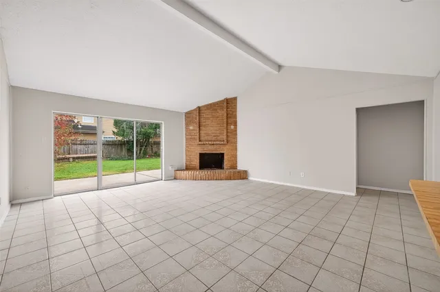 a view of an empty room with a fireplace and a larger window
