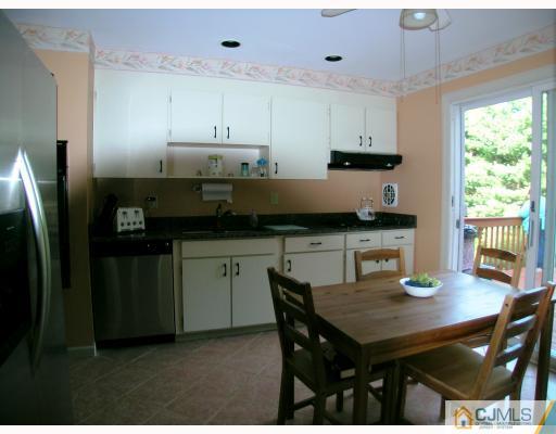 2 Lynnwood Road Edison, NJ 08820 - Photo 5 of 8 a kitchen with stainless steel appliances granite countertop a stove a refrigerator a sink a dining table and chairs with wooden floor