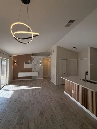 a view of a room with wooden floor gym equipment and a chandelier