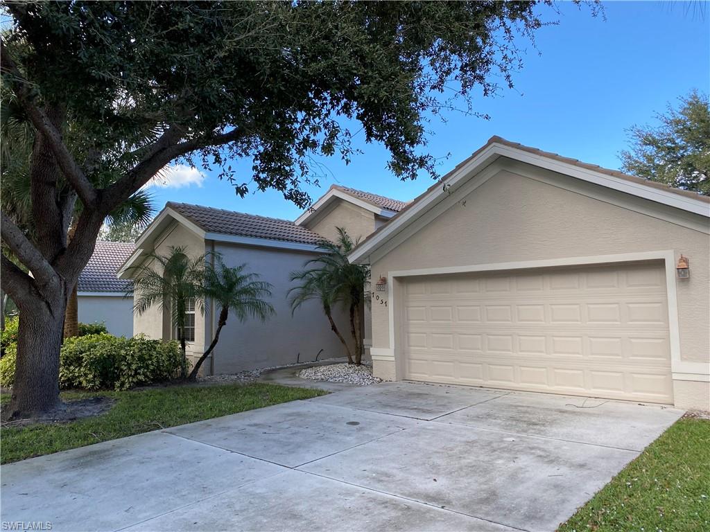 7057 Timberland Circle Naples, FL 34109 - Photo 2 of 22 a view of a white house with a yard and garage